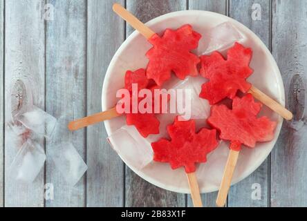 Kanadische Ahorn-Wassermelone knallt auf einer weißen Platte vor einem rustikalen alten Holzhintergrund Stockfoto