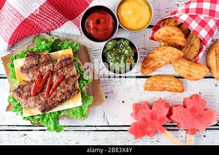 Tages-Picknick-Szene in Kanada mit Hamburgern in Ahorn-Blattform, Wassermelonenknallen und Kartoffelkeilen Stockfoto