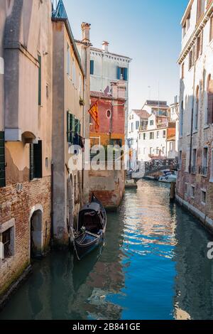 Abseits der Touristengebiete geht es in Venedig, Italien, normal weiter. Wäscherei hängt von den Fenstern, Pflanzen schmücken Balkone, eine Gondel schwebt auf Touristen aus Stockfoto