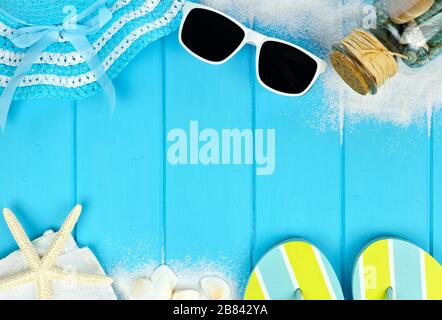 Summer double border of beach items and sea shells on blue wooden background Stockfoto