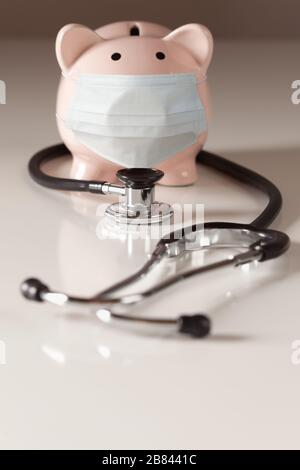 Stethoskop und Piggy Bank tragen medizinische Gesichtsmaske. Stockfoto