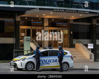 Zwei städtische Polizeibeamte in Madrid unterhalten sich, während sie den Haupteingang des Gran Hotel Colon Hotels in der Innenstadt von Madrid bewachen. Am 19. März ist das Gran Hotel Colon das erste medizinische Hotel in Spanien geworden, in dem Patienten mit leichten Coronavirus-Symptomen behandelt werden. Der Zugriff auf unbefugte Personen ist verboten. Das Hotel verfügt über 365 Zimmer, in denen Patienten mit Coronavirus versorgt werden, um den Druck überfüllter Krankenhäuser zu lindern. Stockfoto