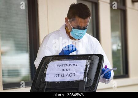 Mitarbeiter im Gesundheitswesen entsorgen den COVID-19-Test im medizinischen Abfalleimer in der Drive-Thru-Klinik Stockfoto