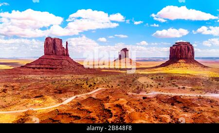 Die Straße kurvt um die aus rotem Sandstein bestehenden Formationen von West mitten, East mitten Buttes und Merrick Butte im Monument Valley an der Grenze zu Utah-Arizona, USA Stockfoto