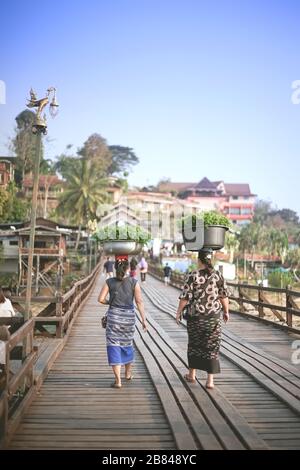 Kanchanaburi, Thailand - 17. Januar 2020: Gemüseverkäufer mit Becken auf dem Kopf laufen auf der Mon Brücke in Sangkhla Buri, Provinz Kanchanaburi Stockfoto