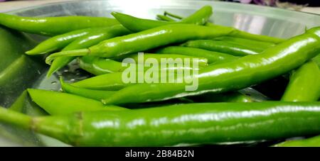 Vollformats-Nahaufnahme eines Bündels von leuchtenden und glänzend grünen Chilipaprippern. Bio-Gemüse auf dem lokalen Lebensmittelmarkt. Stockfoto