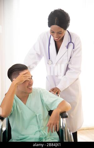 Ein männlicher Patient saß wegen Kopfschmerzen auf dem Rollstuhl. Im Krankenhaus behandelt und von einem Arzt überwacht. Stockfoto