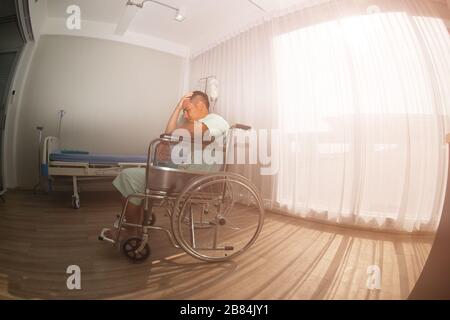 Ein männlicher Patient saß wegen Kopfschmerzen auf dem Rollstuhl. Behandlung im Krankenhaus. Stockfoto