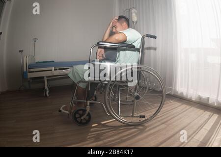 Ein männlicher Patient saß wegen Kopfschmerzen auf dem Rollstuhl. Behandlung im Krankenhaus. Stockfoto