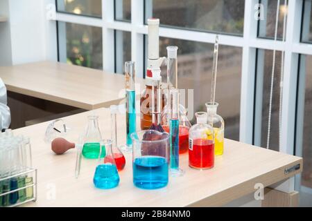 Medizinische Forschungslabors oder Labortestproben oder eine Lösung mit einer Pipette und einem sechsundneunzig-Well-Zelltablett mit Mikroskopen im Hintergrund. Stockfoto