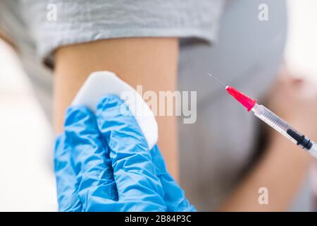 Nahaufnahme eines Arztes, der die Spritze an den weiblichen Patientenarm in der Klinik spritzt Stockfoto