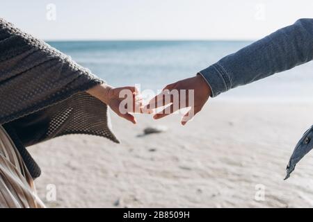 Die Hände eines Paares vor dem Hintergrund des Meeres Strecken sich aufeinander. Stockfoto