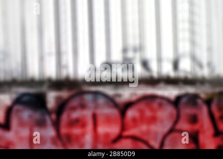 Verschwommenes Bild Graffiti bunt auf Wandziegel für Hintergrund, schmutzige Farbe bunt Flecken auf der Wand Hintergrund verwischen Textur rot Stockfoto
