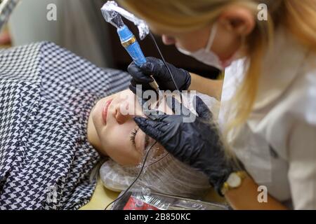 Microblading Augenbrauen Arbeitsablauf in einem Schönheitssalon. Frau mit ihren Augenbrauen getönt. Semi-Permanent Make-up für Augenbrauen. Konzentrieren Sie sich auf das Modell von Gesicht und ey Stockfoto