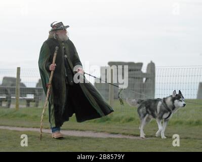 Ein Mann mit Hund steht auf einem Fußweg in der Nähe von Stonehenge in der Salisbury Plain in in Wiltshire, wo die traditionellen Tagundfeste innerhalb der Steine nach English Heritage, das die Attraktion verwaltet, abgebrochen wurden, schloss das Gelände nach Regierungsratschlägen zu Coronavirus bis zum 1. Mai. Stockfoto