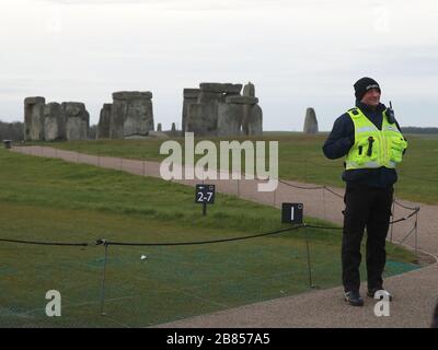 Eine Sicherheitswache steht auf einem Fußweg in der Nähe von Stonehenge in der Salisbury Plain in in Wiltshire, wo die traditionellen Tagundungsfeiern innerhalb der Steine abgebrochen wurden, nachdem English Heritage, das die Attraktion verwaltet, das Gelände nach Regierungsratschlägen zu Coronavirus bis zum 1. Mai geschlossen hatte. Stockfoto