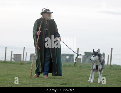 Ein Mann mit einem Hund steht in der Nähe von Stonehenge in der Salisbury Plain in in Wiltshire, wo die traditionellen Äquinoktialfeiern innerhalb der Steine nach English Heritage, das die Attraktion verwaltet, abgebrochen wurden, schloss das Gelände nach Regierungsratschlägen zu Coronavirus bis zum 1. Mai. Stockfoto