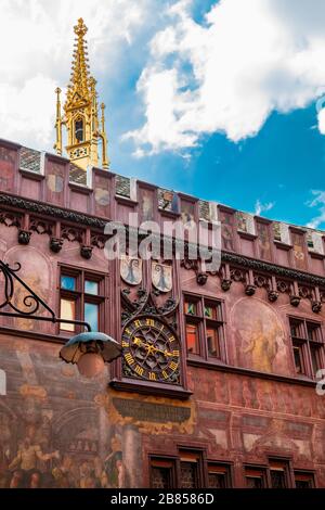 Schöner Blick auf die Mauer mit der Uhr und dem goldenen Turm im Innenhof des Rathauses in Basel. Es ist charakteristisch für sein rotes... Stockfoto