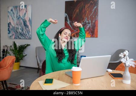 Junge Frau mit geschlossenen Augen, die sich in einem Stuhl ausdehnt. Stockfoto