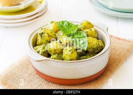 Gnocchi mit "Pesto"-Sauce, in Terrakotta Schüssel, auf weißem Holzbärgrund Stockfoto