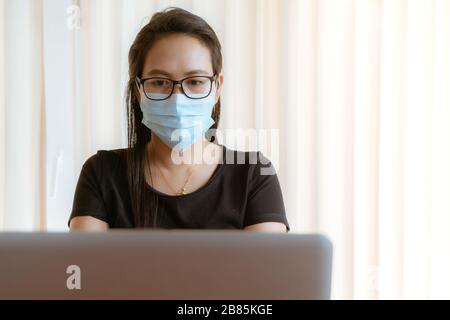 Frau mit Gesichtsmaskenschutz während der Arbeit zu Hause während des Coronavirus- oder Covid-19-Ausbruchs Stockfoto