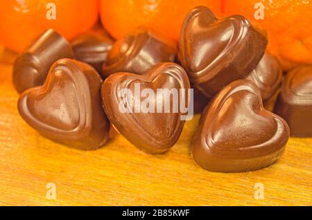 Schokoladenbonbons und Orange auf einem Holztisch Stockfoto