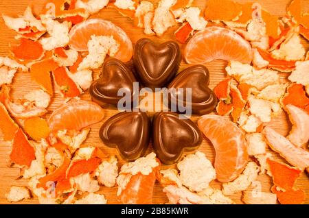 Schokoladenbonbons und frische Mandarinen auf einem Holztisch Stockfoto