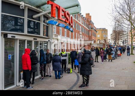 London, Großbritannien. März 2020. Einige sind maskiert, aber es gibt keine soziale Distanzierung - EINE Warteschlange wartet geduldig auf die Tescos in Clapham South aufgrund von Coronavirus (Covid 19) Engpässen - Hoden hat Rationierungen eingeführt, die zum Beispiel seltsam Ermöglicht den Kauf von 27 toilettenrollen, aber nur 2 Dosen Konservenmakrelen pro Besuch. Credit: Guy Bell/Alamy Live News Stockfoto