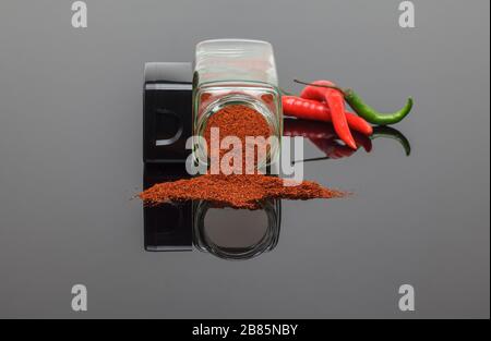 Heißes Chilipulver, das mit frischen Chilis aus Gewürzbecher gießt Stockfoto