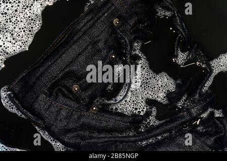 Jeans blau dunkel in Schwammwäsche und nass in Schwammwasser schmutzig schwarz, farbige Jeanskleidung Stockfoto