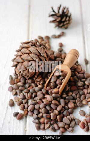 Zedernmuttern aus Holzschaufel über dem Haufen von Zedernnüssen Stockfoto