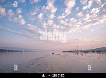 Fischer gehen aus, um Fänge aus Töpfen zu sammeln. Sonnenaufgang über dem Genfersee, während die Besatzung und ihr kleines Boot von der Küste aus fahren, um ihren Fang zu überprüfen Stockfoto