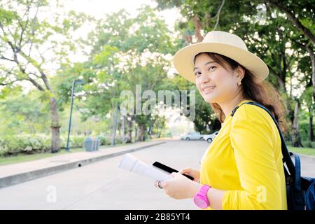 Touristen von Frauen suchen mithilfe von Smartphones nach Touristeninformationen. In der Hand sind ausführliche Bücher über interessante Attraktionen. Stockfoto