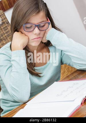 Schöne Schülerin macht ihre Hausaufgaben ohne Motivation Stockfoto
