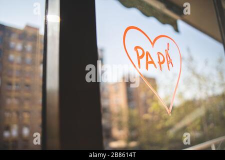 Auf einem Fenster mit Gebäuden auf dem Hintergrund ist ein Herz gewettich rote Kreide gezeichnet. Zeichnung zur Feier des Vatertags während des Alarmstatus in der Mitte Stockfoto