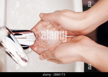 Mann waschen seifige Hände im Badezimmer unter fließendem Wasser. Draufsicht. Stockfoto