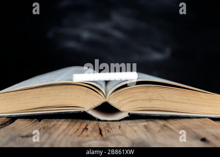 Zurück zum Schulkonzept, zum Bildungserfolg. Bücher, die auf dem Tisch und oben platziert sind, sind Kreide. Der Hintergrund ist eine leere Tafel, die gestellt werden kann Stockfoto