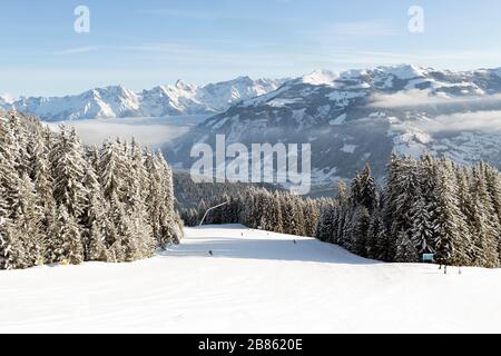 Skipisten und schneebedeckte Tannen im Ferienort Zell am See in Österreich. Stockfoto