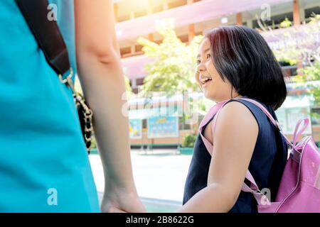 Zurück zum Schulkonzept. Mädchen, die mit Absicht zum Studium reisen, hat sie einen roten Rucksack. Sie plaudert glücklich mit ihrer Mutter. Stockfoto