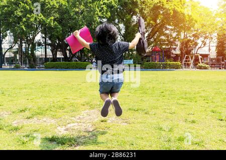 Zurück zum Schulkonzept. Mädchen, die mit Absicht zum Studium reisen und fröhlich springen. Sie reist zum Musikstudium, mit Musiknoten und Ukulele. Stockfoto