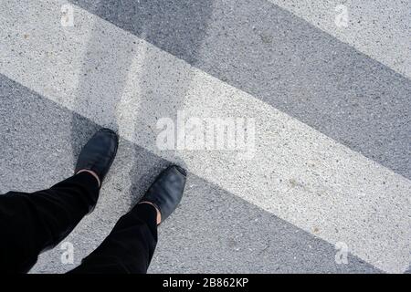 Männer, die über den Querswalk laufen, streckte sein Schatten aus. Stockfoto