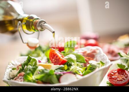 Flasche mit Olivenöl in Salat gießen Stockfoto