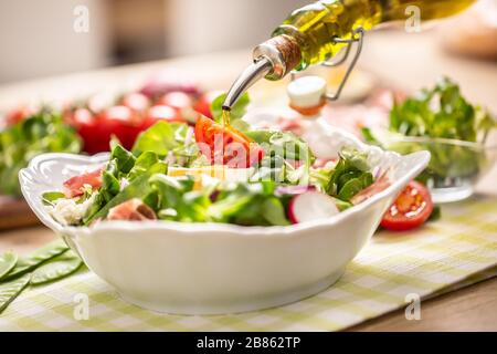 Flasche mit Olivenöl in Salat gießen Stockfoto