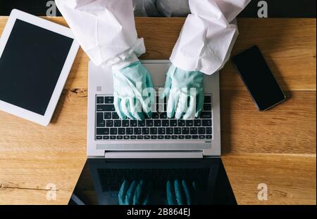 Eine Frau arbeitet von zu Hause aus mit dem Laptop, dem digitalen Tablet und dem Handy im Wohnzimmer, ausgestattet mit Sicherheitsmaßnahmen gegen einen Virus-Preventio Stockfoto