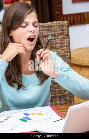 Schöne müde Mädchen Studentin macht ihre Hausaufgaben beim Gähnen Stockfoto