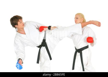 Junge Karateka-Schüler in weißen Kimono-Schwarzgurten im Kampfhandschuhzug trainieren Schläge mit Tritten und Händen auf weißem Hintergrund. Professiona Stockfoto