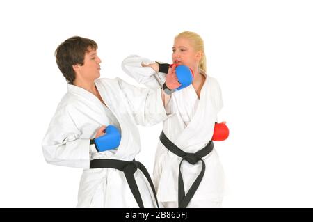 Junge Karateka-Schüler in weißen Kimono-Schwarzgurten im Kampfhandschuhzug trainieren Schläge mit Tritten und Händen auf weißem Hintergrund. Professiona Stockfoto