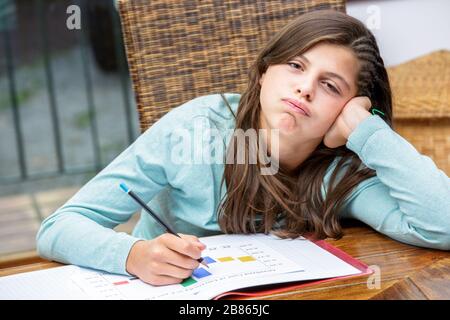 Schöne Schülerin macht ihre Hausaufgaben ohne Motivation Stockfoto