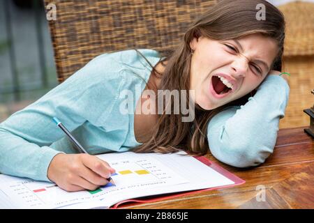 Schöne müde Mädchen Studentin macht ihre Hausaufgaben beim Gähnen Stockfoto