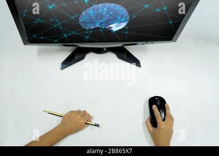 Innovatives Lernkonzept. Die Hand des Kindes, mit der eine Maus zum Bedienen des Computers und anderer Geräte gehalten wurde, war ein Bleistift. Der Bildschirm ist leer. Stockfoto